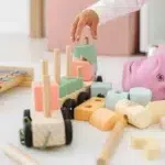 Dete na podu slaže drveni vozić u pastelnim bojama