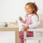 Devojčica sedi i drži šoljicu iz Pino drvenog seta za čaj